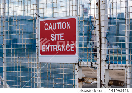 Caution site entrance warning sign on perimeter fence Caution site entrance warning sign on perimeter fence 141998468
