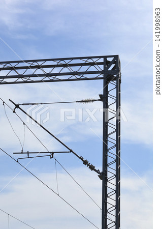 Railway overhead line steel gantry with catenary wires against blue sky Railway overhead line steel gantry with catenary wires against blue sky 141998963