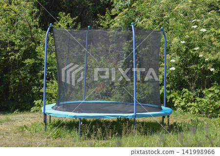 Large trampoline with a safety net in the backyard garden Large trampoline with a safety net in the backyard garden 141998966