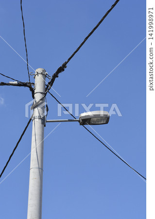 Street light on a concrete pole against the blue sky Street light on a concrete pole against the blue sky 141998971