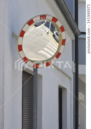 Convex traffic mirror mounted on a building wall Convex traffic mirror mounted on a building wall 141998973