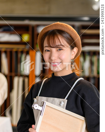 一位面帶微笑的女士在她的工作室裡拿著一塊板材。 一位面帶微笑的女士在她的工作室裡拿著一塊板材。 141999328
