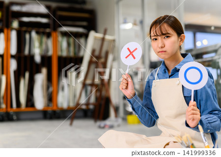 A woman holding a circle/cross sign in her studio A woman holding a circle/cross sign in her studio 141999336
