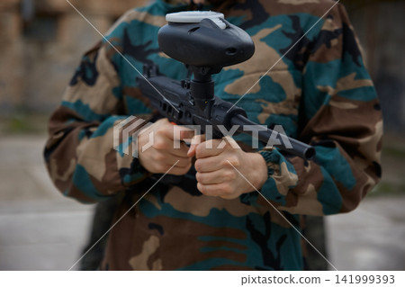 A soldier, wearing military clothes is holding a weapon in his hands A soldier, wearing military clothes is holding a weapon in his hands 141999393