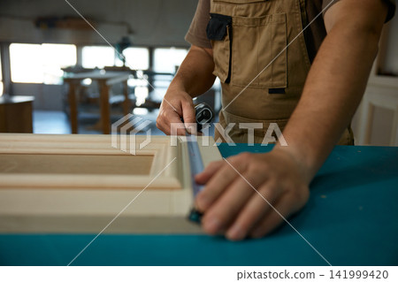 Precision measuring for cabinet edge alignment, hands using ruler and gauge to ensure exact fit Precision measuring for cabinet edge alignment, hands using ruler and gauge to ensure exact fit 141999420