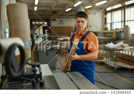 Artisan scrutinizes raw wooden materials stored on workshop shelves for crafting furniture pieces Artisan scrutinizes raw wooden materials stored on workshop shelves for crafting furniture pieces 141999448