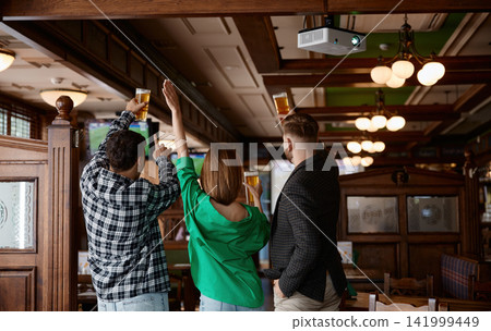 Friends celebrating with raised beers, young coworkers and supporters 141999449