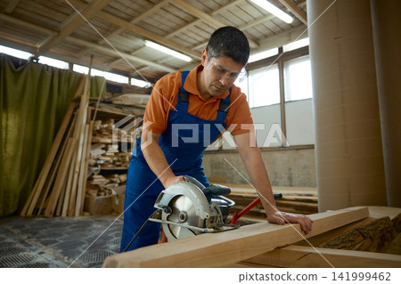 Professional artisan utilizes circular saw to carve wood securely with safety measures Professional artisan utilizes circular saw to carve wood securely with safety measures 141999462