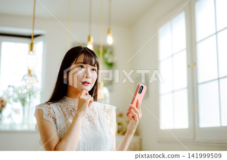 A woman thinking with her smartphone in her hand. A woman thinking with her smartphone in her hand. 141999509