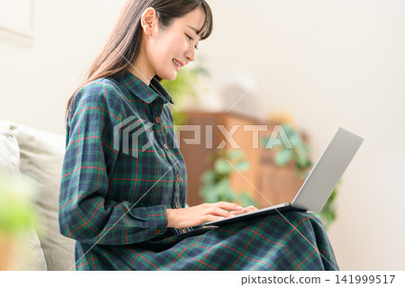 一位身穿格子連身裙的女士正在使用筆記型電腦。 一位身穿格子連身裙的女士正在使用筆記型電腦。 141999517