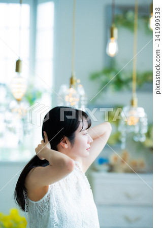 A woman wearing lace clothing and styling her hair. A woman wearing lace clothing and styling her hair. 141999538