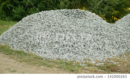 Macadam crushed stone gravel aggregate angular rocks granite, basalt, construction of roads, highways and houses, limestone gravel mound shaped heap light gray macadam stone piled layered patch trees Macadam crushed stone gravel aggregate angular rocks granite, basalt, construction of roads, highways and houses, limestone gravel mound shaped heap light gray macadam stone piled layered patch trees 142000263