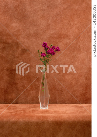 A branch of flowers in a glass vase on a brown background A branch of flowers in a glass vase on a brown background 142000355