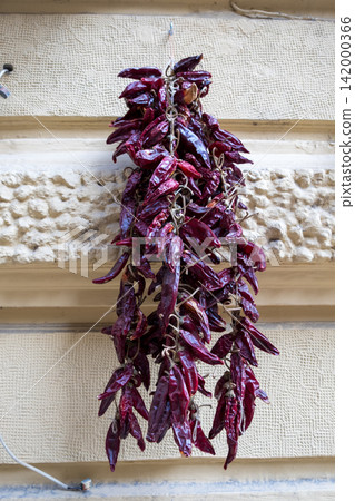 Dried red chili peppers hanging on rustic wall 142000366