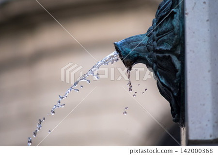 Water flowing from an old bronze fountain spout 142000368