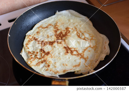 Homemade crepe cooking in frying pan Homemade crepe cooking in frying pan 142000387