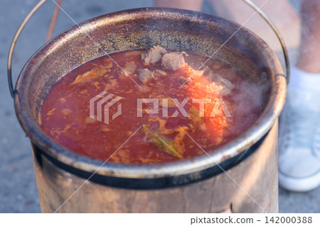 Steaming meat stew in a rustic outdoor pot Steaming meat stew in a rustic outdoor pot 142000388