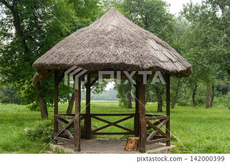 Wooden thatched gazebo in a green park Wooden thatched gazebo in a green park 142000399