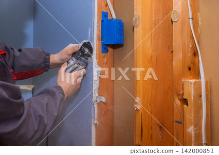 Contractor uses power oscillating multi tool to cut through wall in construction area. Contractor uses power oscillating multi tool to cut through wall in construction area. 142000851