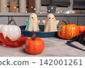 Festive halloween ghost desserts with pumpkins and autumn decor on table 142001261