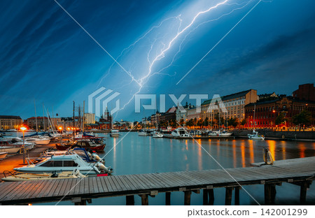 HELSINKI, FINLAND. spectacular, powerful lightning bolt strikes from a dark stormy sky over the harbor and waterfront architecture in Helsinki, Finland at night HELSINKI, FINLAND. spectacular, powerful lightning bolt strikes from a dark stormy sky over the harbor and waterfront architecture in Helsinki, Finland at night 142001299