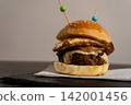 Artisan breakfast sandwich with fried egg, beef patty, and caramelized onions 142001456