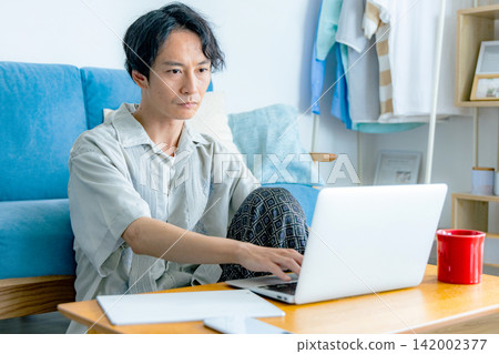 一個男人在客廳裡一邊喝咖啡一邊思考。 142002377