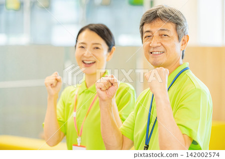 身穿polo衫的老年男女員工在一家養老院工作。 身穿polo衫的老年男女員工在一家養老院工作。 142002574