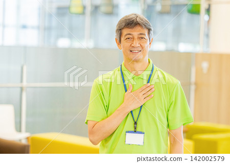 A senior male staff member with white hair working at a facility for the elderly A senior male staff member with white hair working at a facility for the elderly 142002579