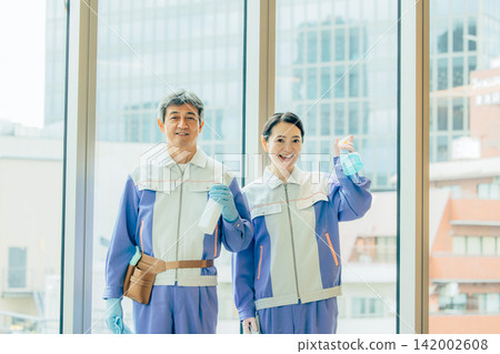 Senior male and female staff members standing in the office wearing cleaning uniforms. 142002608