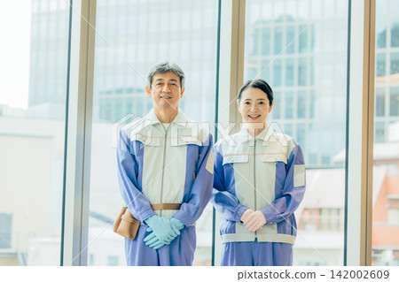 Senior male and female staff members standing in the office wearing cleaning uniforms. Senior male and female staff members standing in the office wearing cleaning uniforms. 142002609