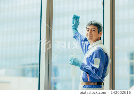 一個穿著工作服的男人站在窗邊。 一個穿著工作服的男人站在窗邊。 142002616