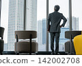 一位資深商人背對著鏡頭，從辦公室的窗戶眺望城市。 142002708