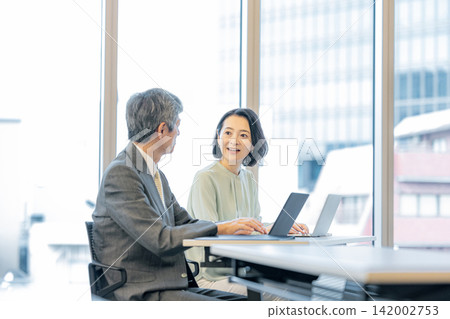 辦公室裡,高階男女員工工作的商務場景 辦公室裡,高階男女員工工作的商務場景 142002753