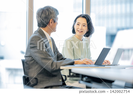 辦公室裡,高階男女員工工作的商務場景 辦公室裡,高階男女員工工作的商務場景 142002754