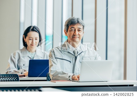 一名六十多歲的男性員工,身穿工作服,正在辦公室使用筆記型電腦。 一名六十多歲的男性員工,身穿工作服,正在辦公室使用筆記型電腦。 142002825