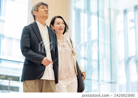 A scene of a senior couple traveling, entering a hotel lobby. A scene of a senior couple traveling, entering a hotel lobby. 142002890