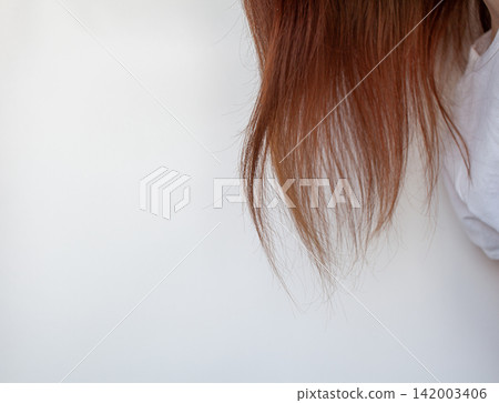 A woman's head with a parting of gray hair that has grown roots due to quarantine. Brown hair on a woman's head close-up. A woman's head with a parting of gray hair that has grown roots due to quarantine. Brown hair on a woman's head close-up. 142003406