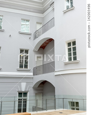 Modern architectural elements with gray walls and balconies, showcasing large windows in a contemporary building courtyard area Modern architectural elements with gray walls and balconies, showcasing large windows in a contemporary building courtyard area 142003496