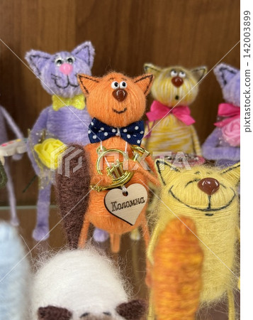Kolomna, Russia - April 06, 2026: Colorful felt cat figurines are arranged on a shelf, showcasing an orange cat with a bow tie and musical instrument Kolomna, Russia - April 06, 2026: Colorful felt cat figurines are arranged on a shelf, showcasing an orange cat with a bow tie and musical instrument 142003899