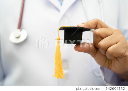 Asian woman doctor holding graduation hat in hospital, Medical education concept. Asian woman doctor holding graduation hat in hospital, Medical education concept. 142004132
