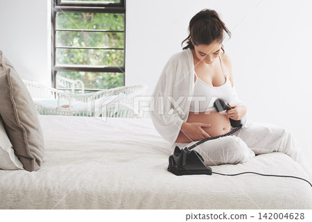 Pregnant woman, relax and phone call by stomach for communication, happiness and contact in bedroom. Mother, smile and conversation in house for care, connection and telephone on tummy for listening Pregnant woman, relax and phone call by stomach for communication, happiness and contact in bedroom. Mother, smile and conversation in house for care, connection and telephone on tummy for listening 142004628