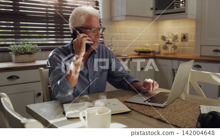 Laptop, phone call and mature man in home with customer service consultation for online crm. Technology, cellphone and male technical support agent on mobile discussion with computer in kitchen. Laptop, phone call and mature man in home with customer service consultation for online crm. Technology, cellphone and male technical support agent on mobile discussion with computer in kitchen. 142004648