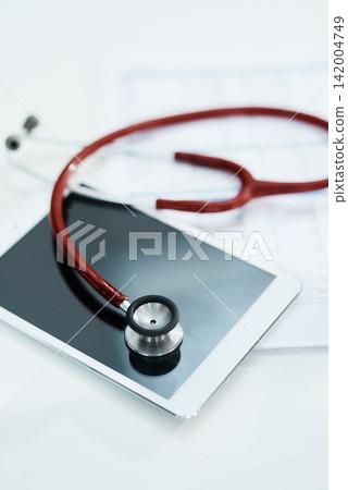 Hospital, telehealth and tablet with stethoscope on desk for medical website, healthcare and research. Documents, cardiology and digital tech, equipment and clipboard for online consulting service Hospital, telehealth and tablet with stethoscope on desk for medical website, healthcare and research. Documents, cardiology and digital tech, equipment and clipboard for online consulting service 142004749