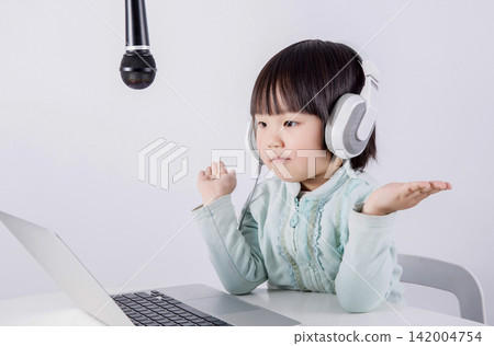 Cute Little Asian Girl Wearing Headphones and Using Microphone with Laptop for Online Music Lesson or Podcast Cute Little Asian Girl Wearing Headphones and Using Microphone with Laptop for Online Music Lesson or Podcast 142004754