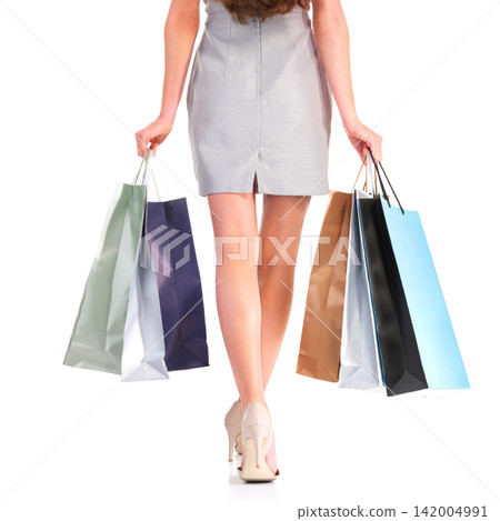 Fashion, shopping bags and legs of woman with presents in studio for deal, sale or discount for luxury. Paper packet, gifts and closeup of female person feet with heels isolated by white background. 142004991