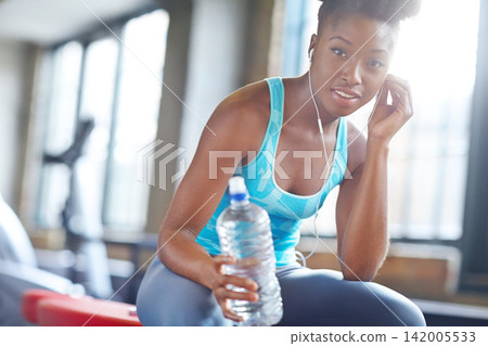 Portrait, health and black woman with water, listening music and fitness with progress and peace. Face, African person and athlete with hydration, training and song for exercise and relax with break Portrait, health and black woman with water, listening music and fitness with progress and peace. Face, African person and athlete with hydration, training and song for exercise and relax with break 142005533