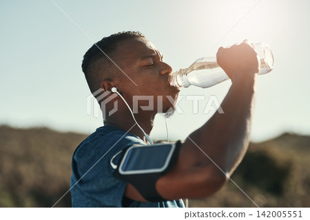 Black man, drink water and music in outdoors for running, thirst and hydrate on sports break. Person, profile and mineral liquid in bottle for nutrition, athlete and phone app for streaming song Black man, drink water and music in outdoors for running, thirst and hydrate on sports break. Person, profile and mineral liquid in bottle for nutrition, athlete and phone app for streaming song 142005551