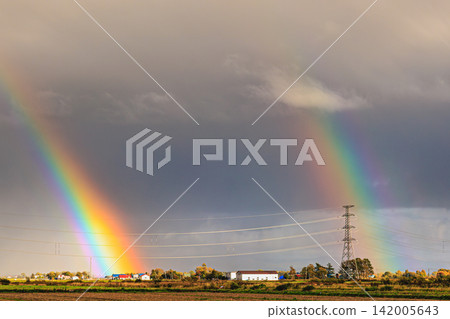 A clear and beautiful double rainbow stretches across the sky above the harvested fields and power lines. A clear and beautiful double rainbow stretches across the sky above the harvested fields and power lines. 142005643