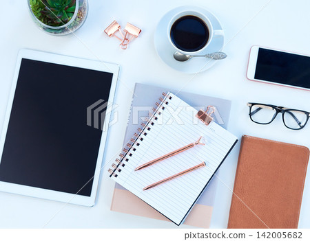 Tablet, notebook and coffee on desk in studio for working, writing notes and planning for career. Creative workplace, business and diary, digital tech and stationery on blue background for job Tablet, notebook and coffee on desk in studio for working, writing notes and planning for career. Creative workplace, business and diary, digital tech and stationery on blue background for job 142005682